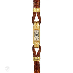 An Art Deco gold cocktail watch centered by a rectangular fa...