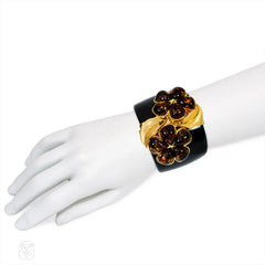 Chunky black acrylic cuff with amber crystal flower motif. Simon Harrison