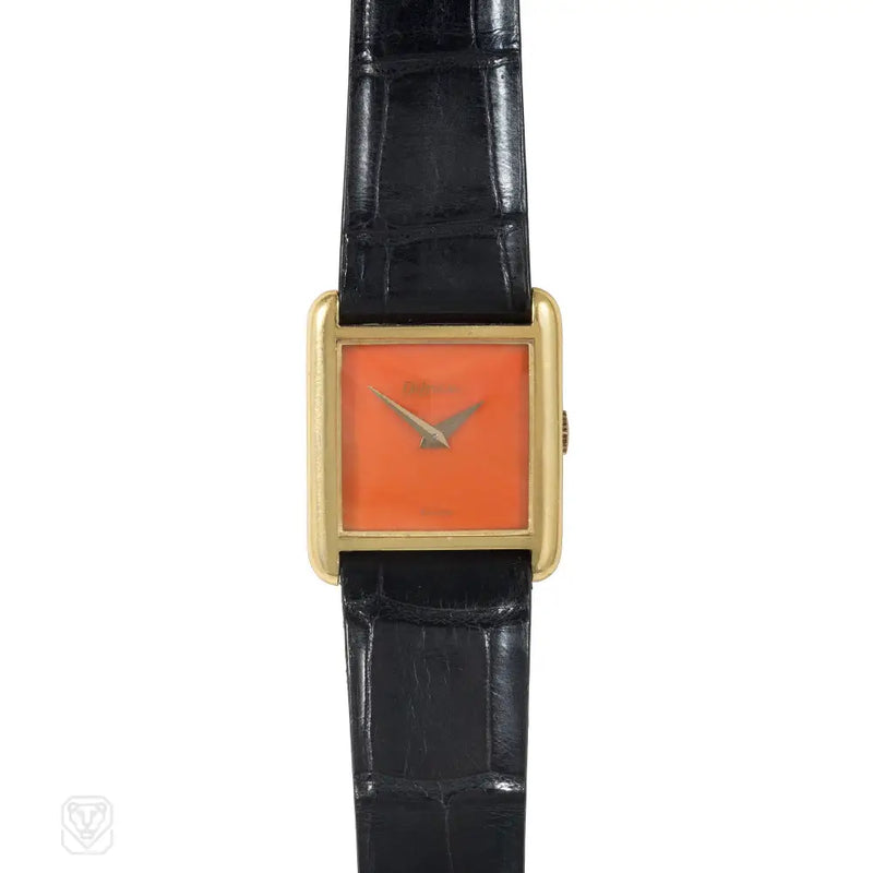 A gold tank watch with a coral face and blued steel dauphine...